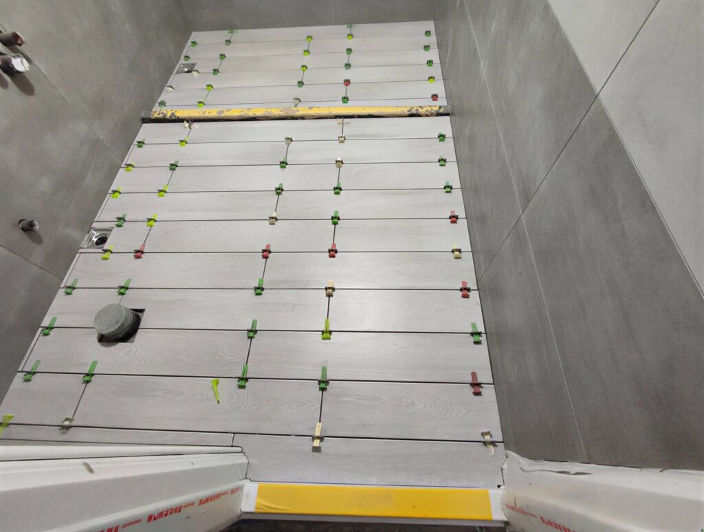 浴室地坪泥作與貼磚施工現場，使用整平器確認平整度與排水條件