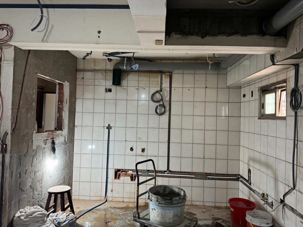 廚房拆除後的水電配管與配線施工現場，顯示牆面管線與設備配置